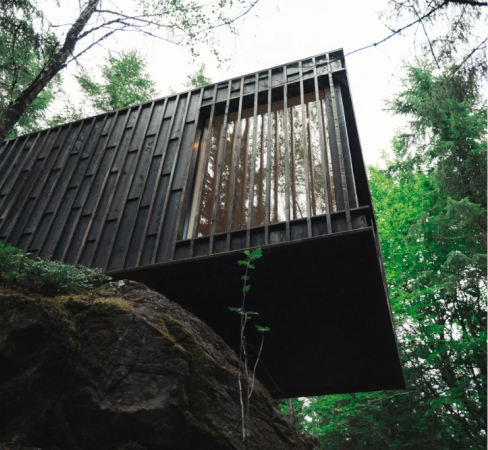 A tree cabin hanging out from a little cliff in the forest