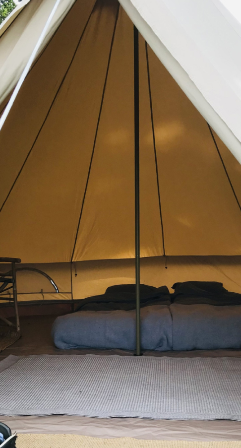 A tent with a mattress on the ground inside the tent 